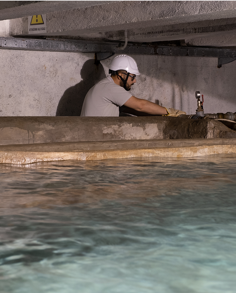 Operaio che lavora su una infrastruttura idrica in cui si vede anche una vasca d'acqua