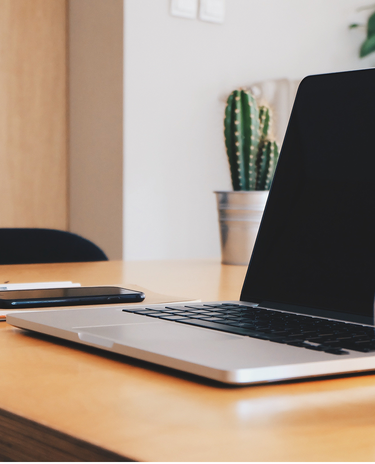 Laptop poggiato su una scrivania d'ufficio. Si vede anche uno smartphone e una pianta di cactus