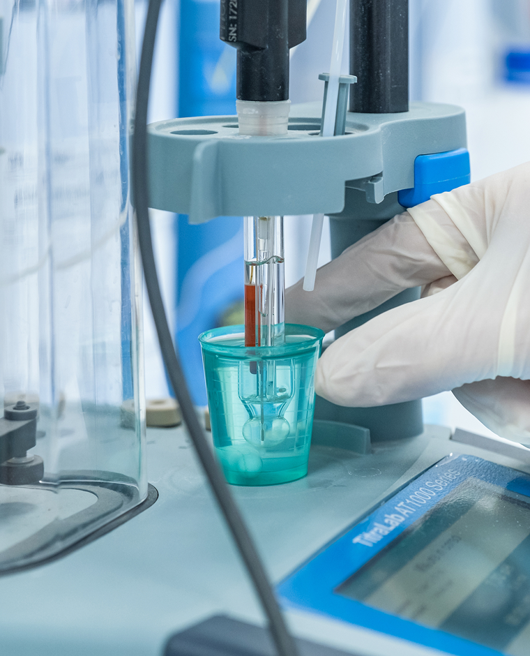 zoom su una mano che tiene in mano una provetta di laboratorio vicino a dei macchinari