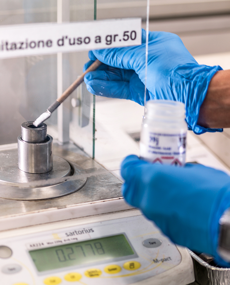 mani che pesano una sostanza su una bilancia in un contesto di laboratorio