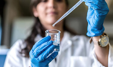 una donna in laboratorio sta versando del liquido in una provetta