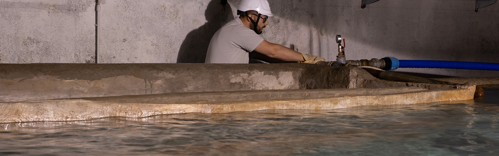 Operaio che lavora su una infrastruttura idrica in cui si vede anche una vasca d'acqua