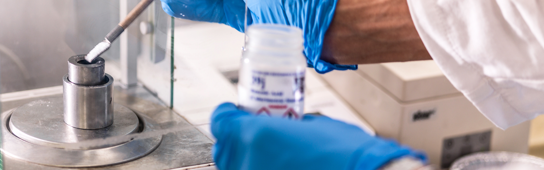 mani che pesano una sostanza su una bilancia in un contesto di laboratorio
