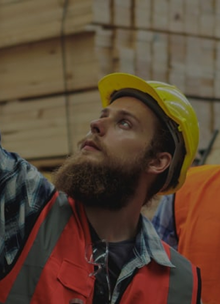 Three workers wearing helmets and vests look at a machine.